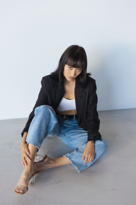 Black blazer and wide jeans, sitting on the studio floor