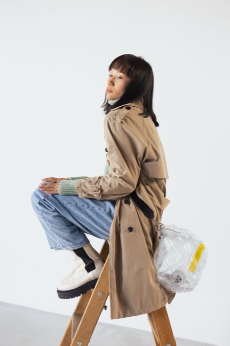 Trench coat and jeans, perched on a wooden ladder