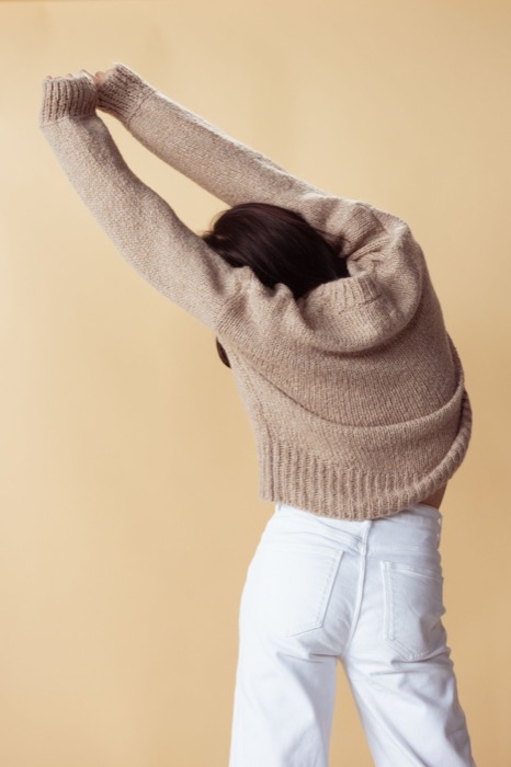 Oatmeal knit jumper from behind, arms stretched overhead