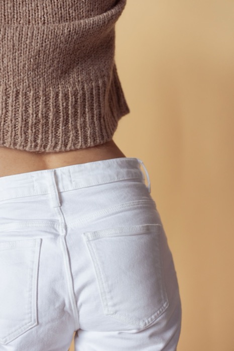 Cropped brown knit over white jeans, back view