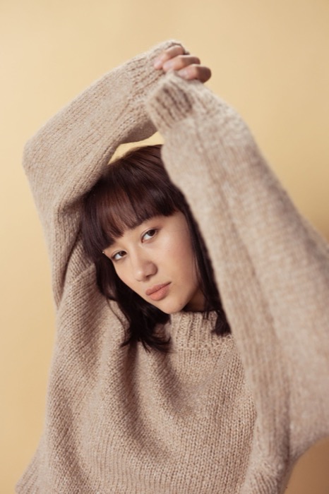 Arms raised in a chunky oatmeal jumper